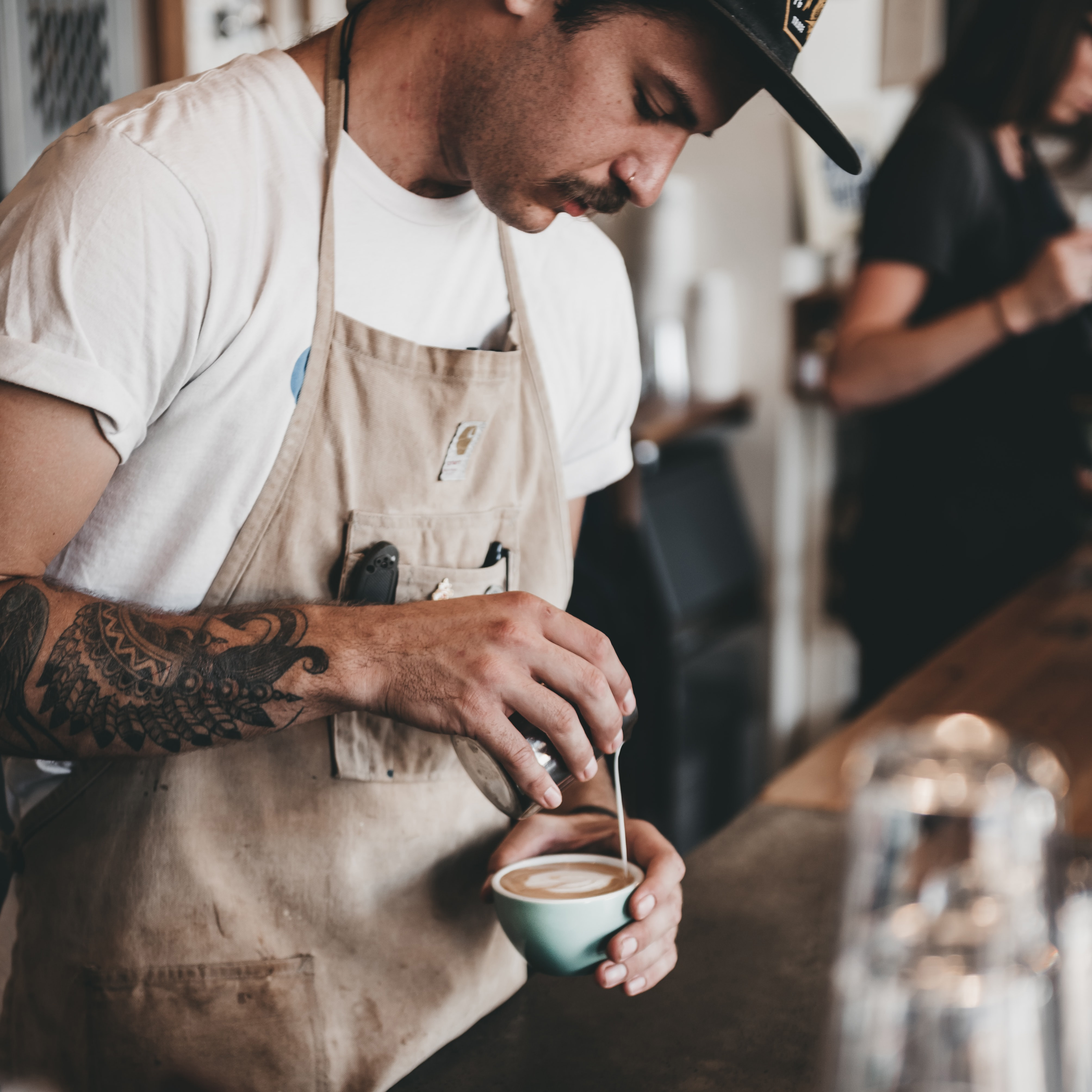 A barista pouring milk into a latte.