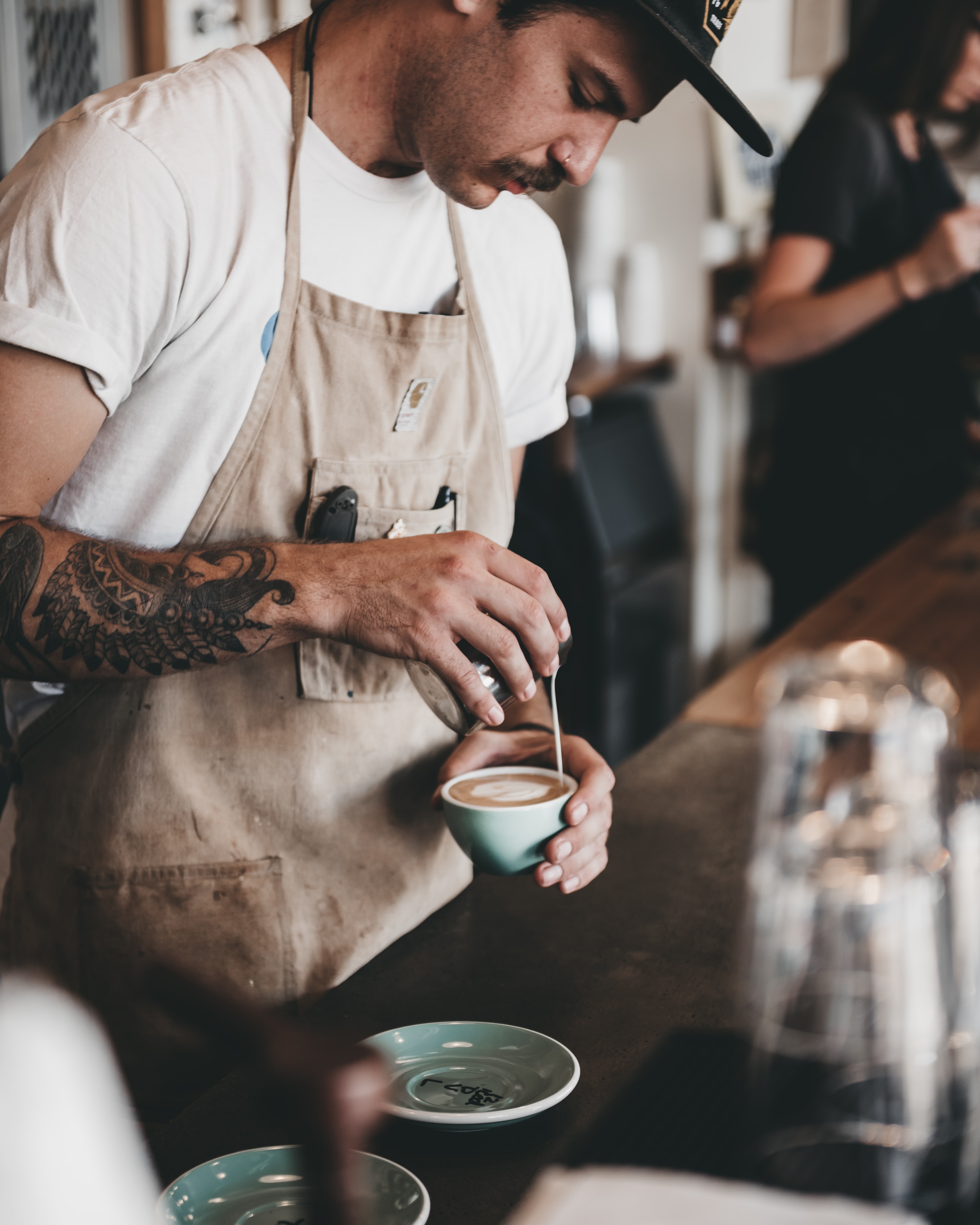 A barista pouring milk into a latte.